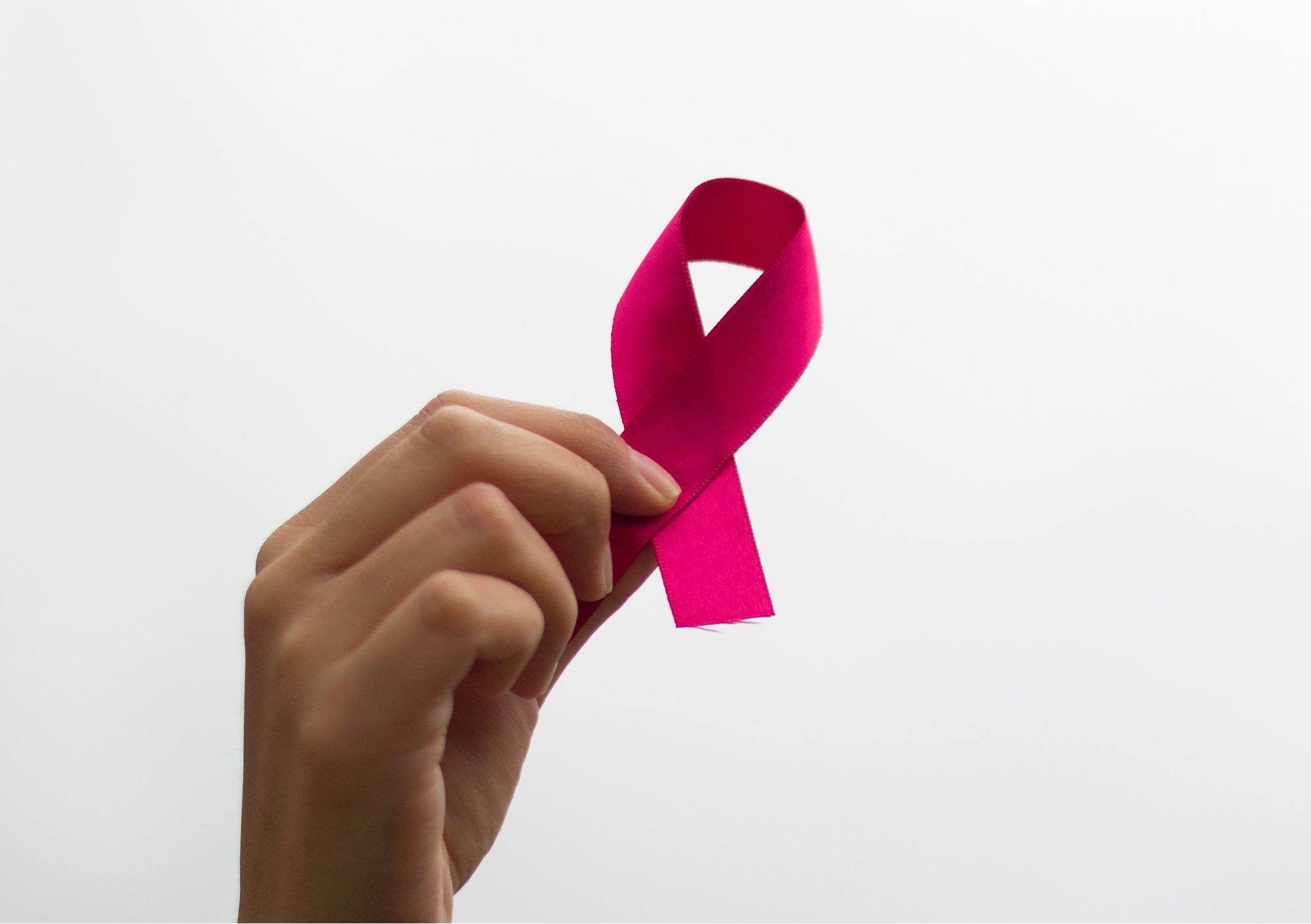 Hand holding breast cancer ribbon